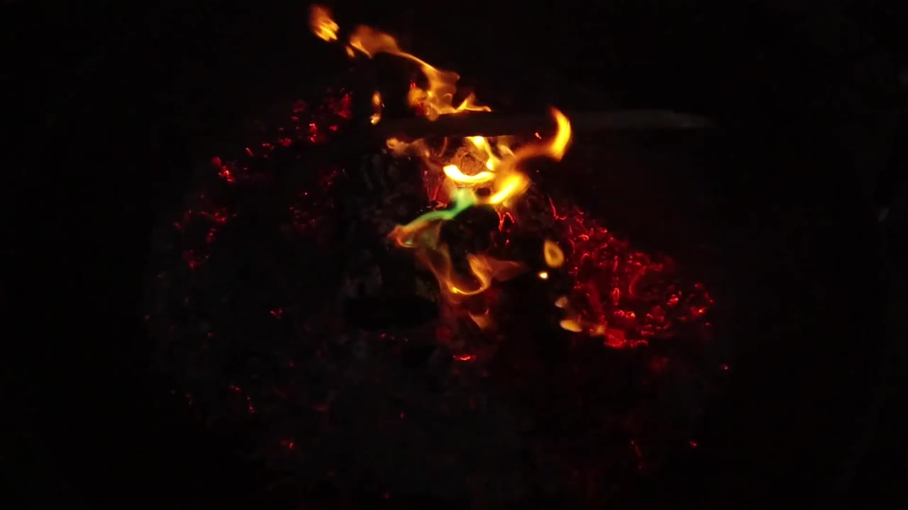 Bright orange flame spreads across red embers in a dark San Clemente, California close view, with no visible people or readable markings.