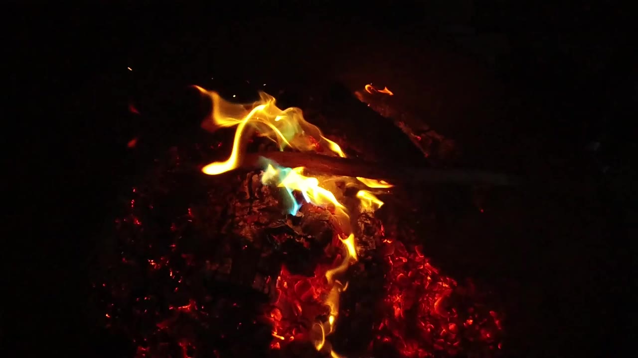Small flames curl above a burning log and embers.