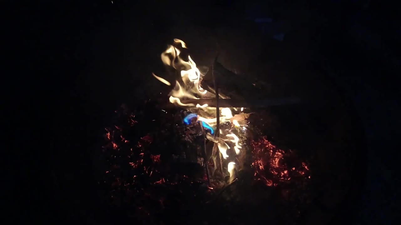 The flames lean lower and stretch across the coals in San Clemente, California, with blue fire visible near the center and no visible people.