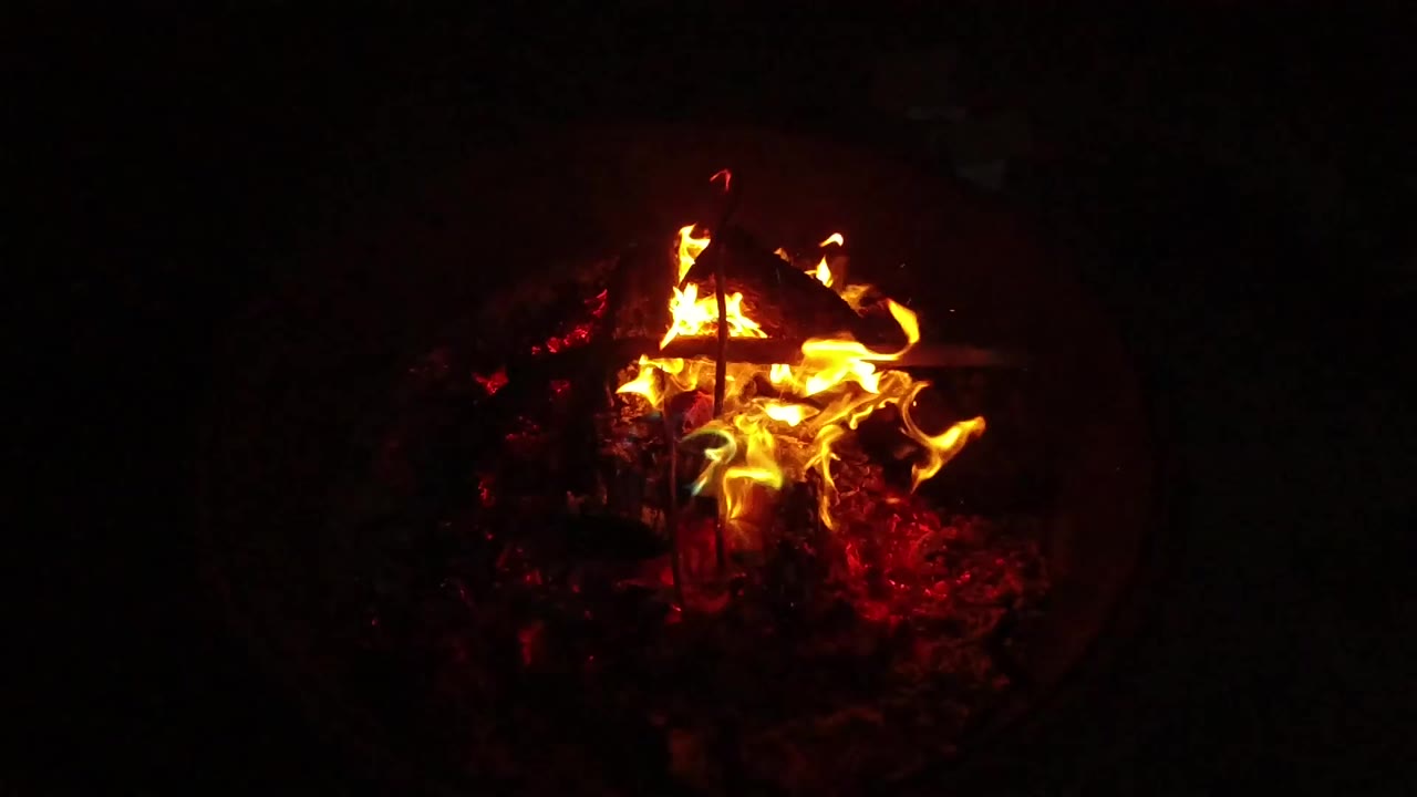 At 0:00, flames rise from crossed sticks in a dark container from the San Clemente, California 2019 clip, with red embers below and no visible people.