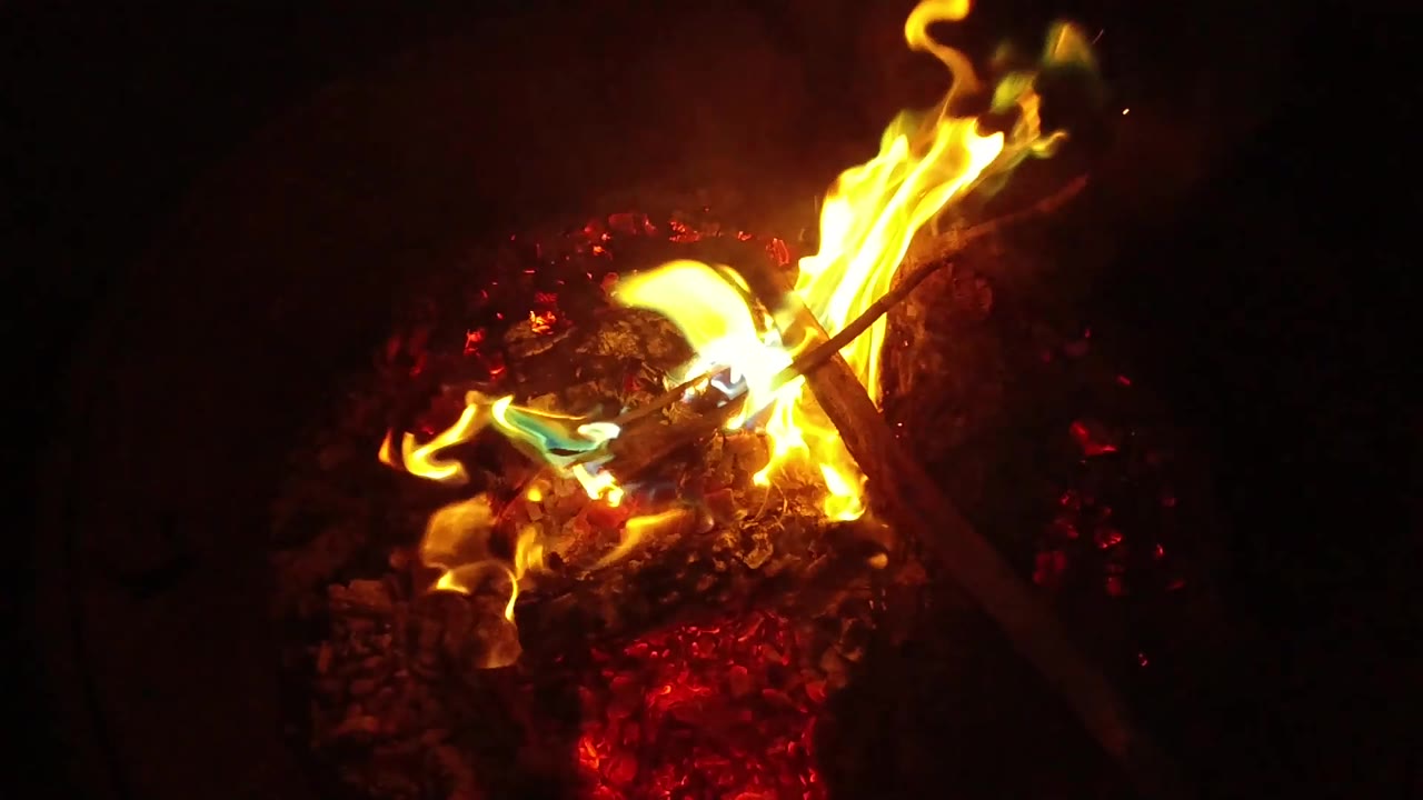 Large yellow flame curls over a bed of glowing embers.