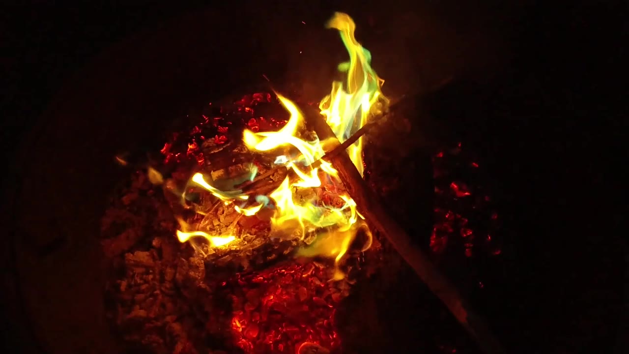 At 0:02, green-blue flame accents appear beside yellow fire over red embers in San Clemente, California, with no visible people in the dark frame.