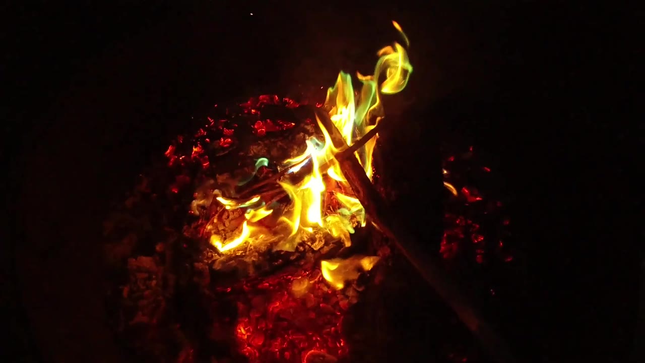 At 0:03, a taller flame rises from the ember bed in San Clemente, California, with the surrounding area falling into shadow and no visible people.