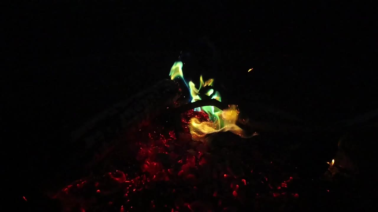 Green and yellow flames burn above red glowing foliage or embers in San Clemente, California, with no visible people.