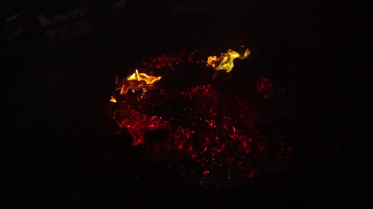 At 0:02, a brighter yellow flame curls near the upper right of the glowing coal bed in the San Clemente fire close-up, with no visible people.