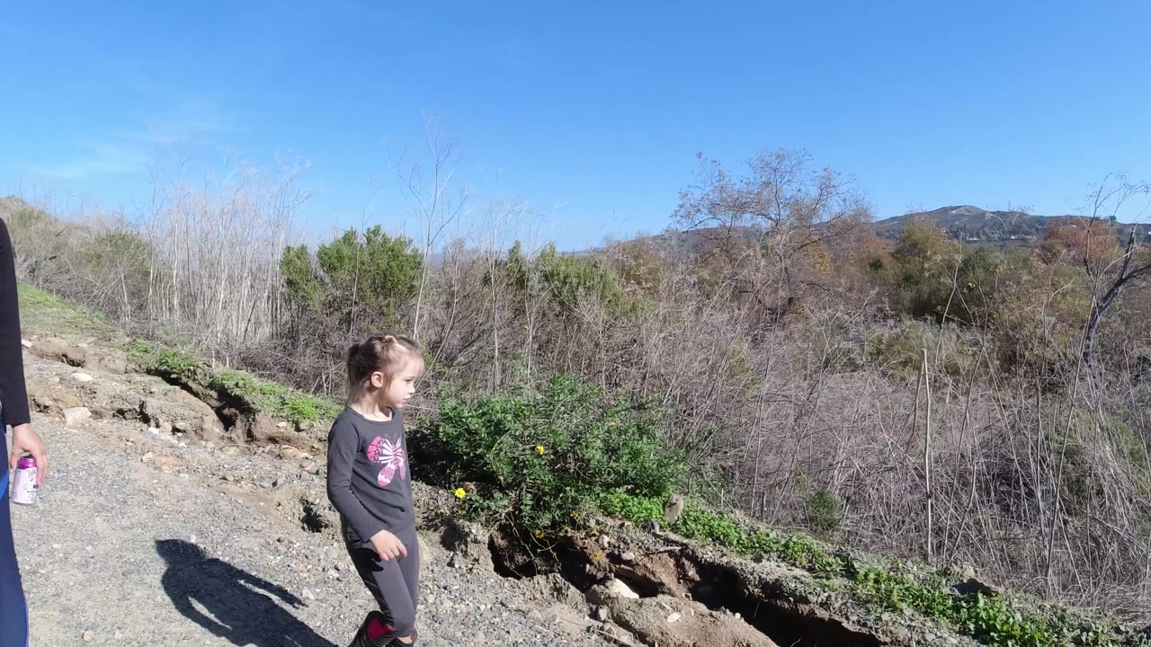 Child on trail with the adult partly cropped at the edge.
