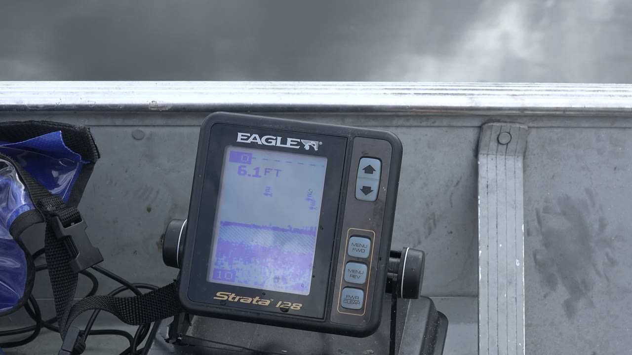 At 0:01, the Eagle display remains centered near the boat rail, its pale purple screen visible with a soft band of Red Lake water beyond and no visible people.