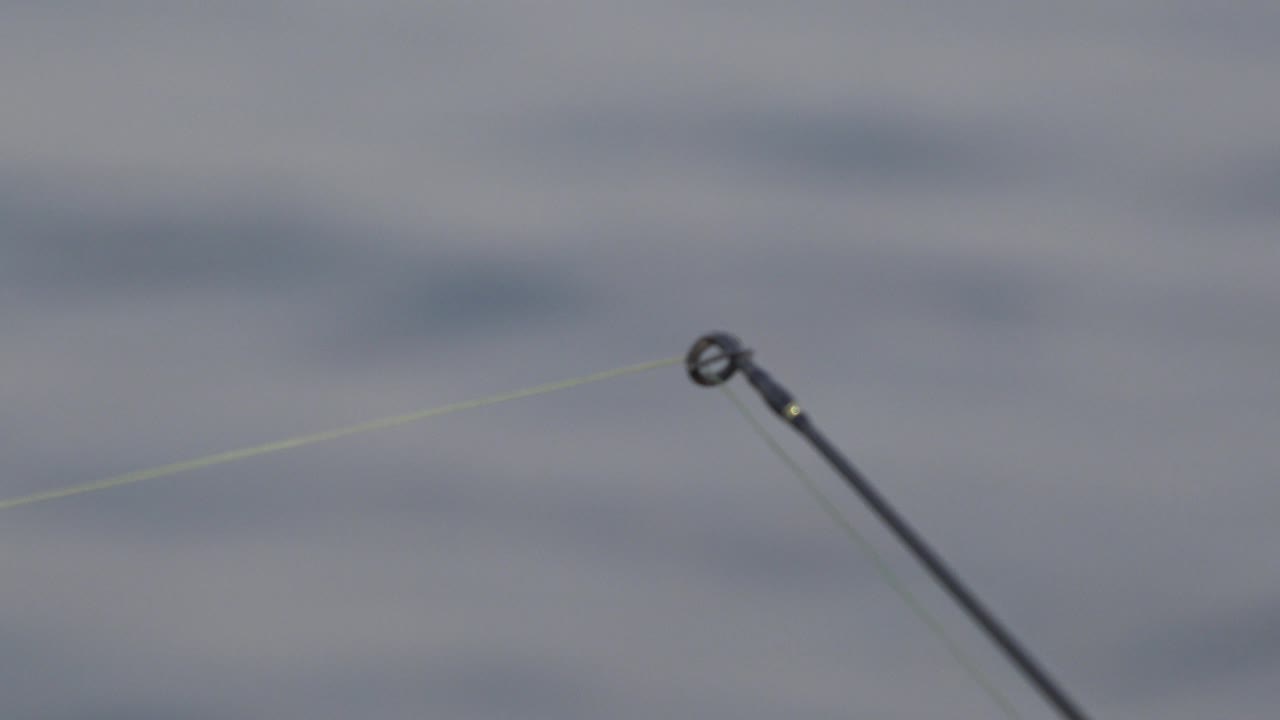 The fishing rod tip sits slightly right of center over blurred gray water in Red Lake, Canada, with no visible people.