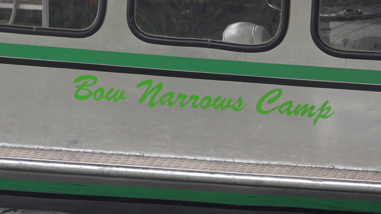 Close view of green Bow Narrows Camp lettering on a docked boat hull.