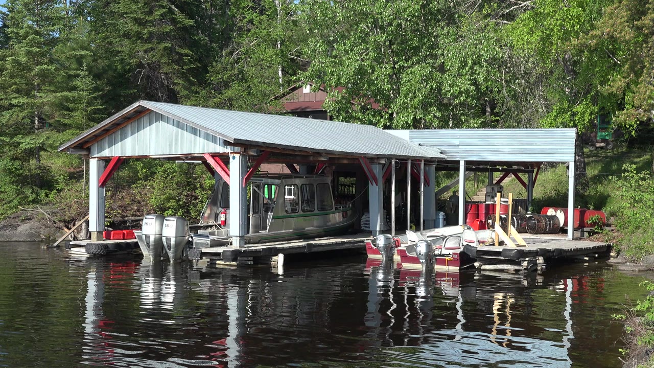Covered lakeside dock with boats on reflective water