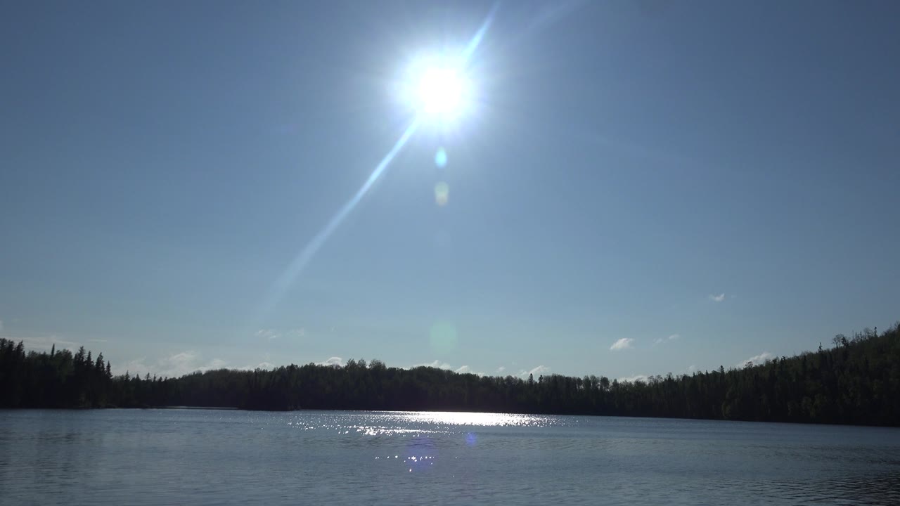 One second into the Red Lake Canada shot, the sun reflection spreads across the lake surface below a dark forest horizon, with no visible people.