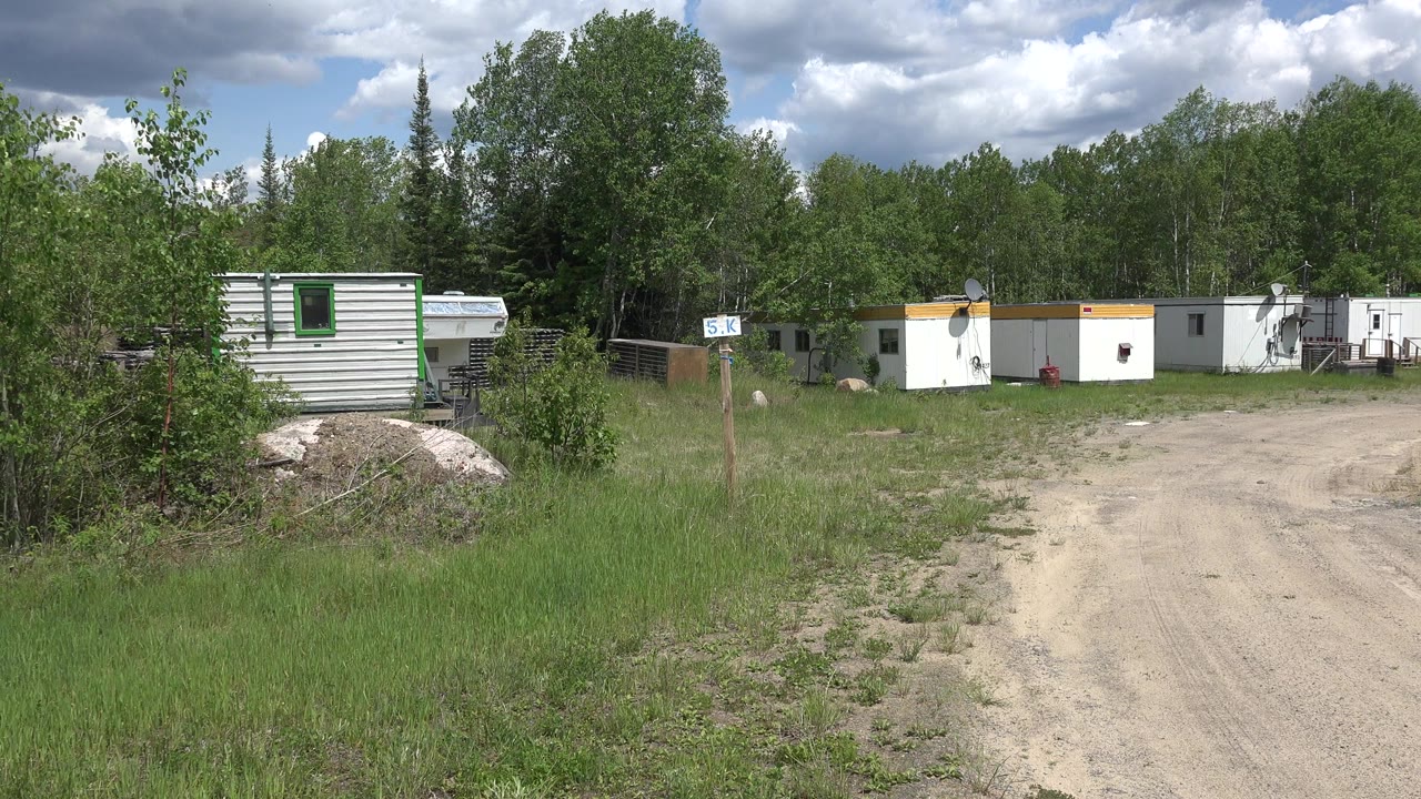 Portable trailers beside a dirt road with trees behind them.