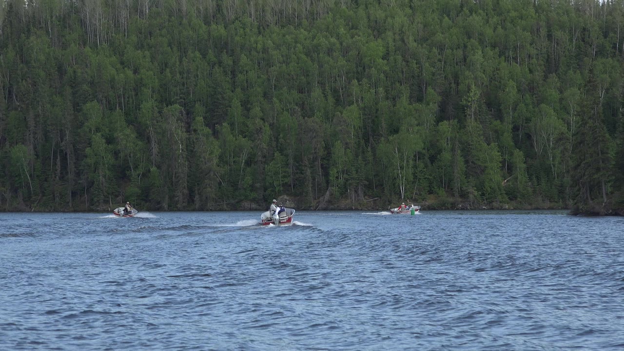 At 0:01 in Red Lake, Canada, the center boat sits farther right on the water while other small boats remain spaced near the forested bank.