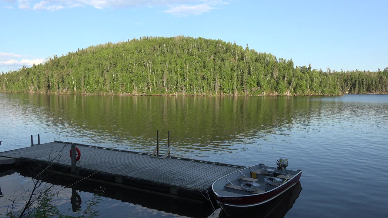 Dock, small boat, lake, and forested shoreline