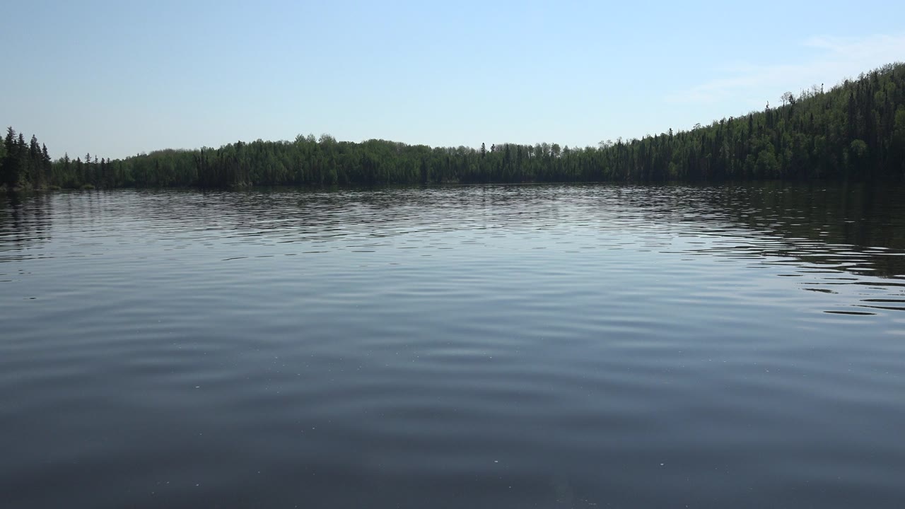 At 0:01, Red Lake, Canada remains framed across open rippled water, with the treeline slightly darker on the right side and no visible people.