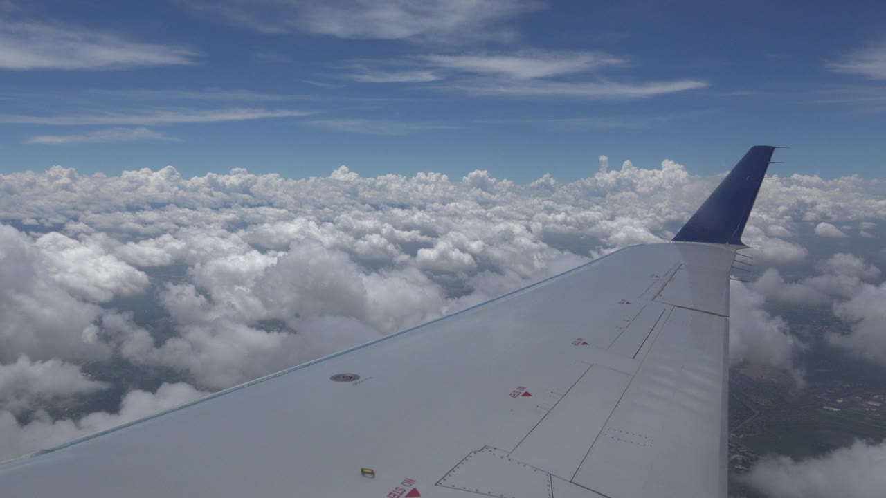 Plane wing crossing cloud field at altitude.
