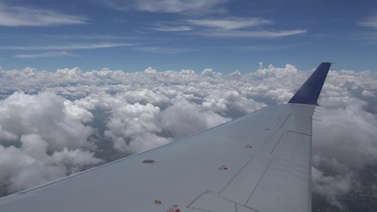 Opening Winnipeg, Canada flight view with a white airplane wing and dark blue wingtip over bright cloud tops, with no visible people.