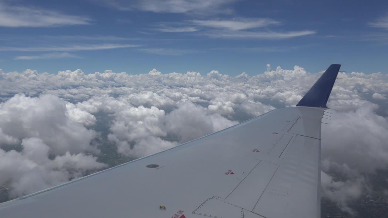 Winnipeg, Canada flight frame with the wing stretching toward a high cloud horizon and patches of darker ground visible between clouds, with no visible people.