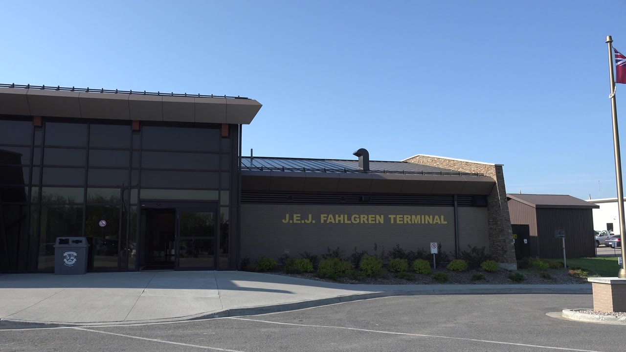 Airport terminal entrance with flagpole and empty curb