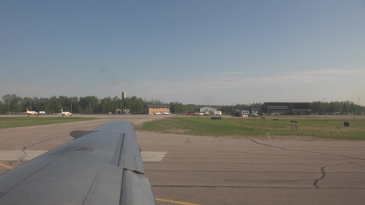 Airplane wing beside runway pavement and airport buildings
