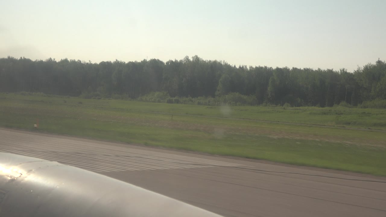 Sun glare on vehicle edge beside striped pavement and fields.