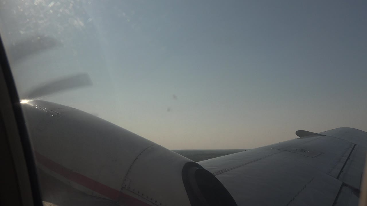 At 0:01, the aircraft wing stretches toward a flat forest horizon in Red Lake, Canada, with muted daylight through the window and no visible people.