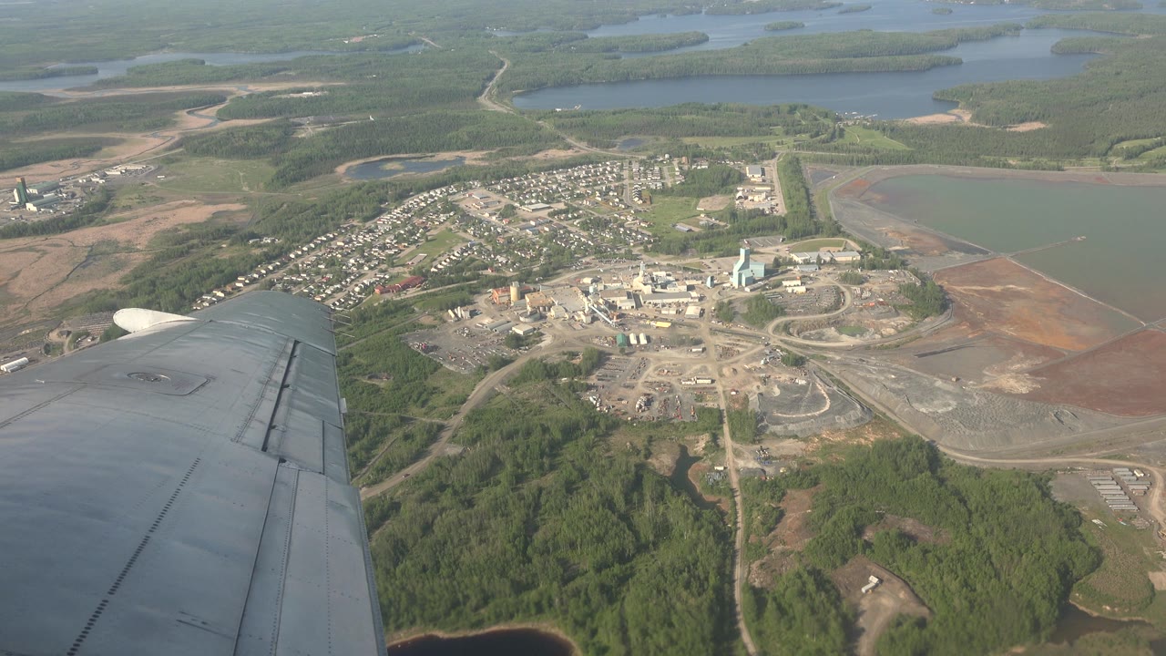 Aerial view of town buildings and lakes with airplane wing.