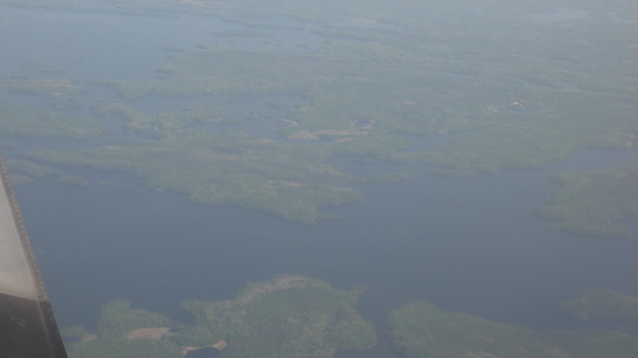 Blue lake and green islands seen past an airplane edge.