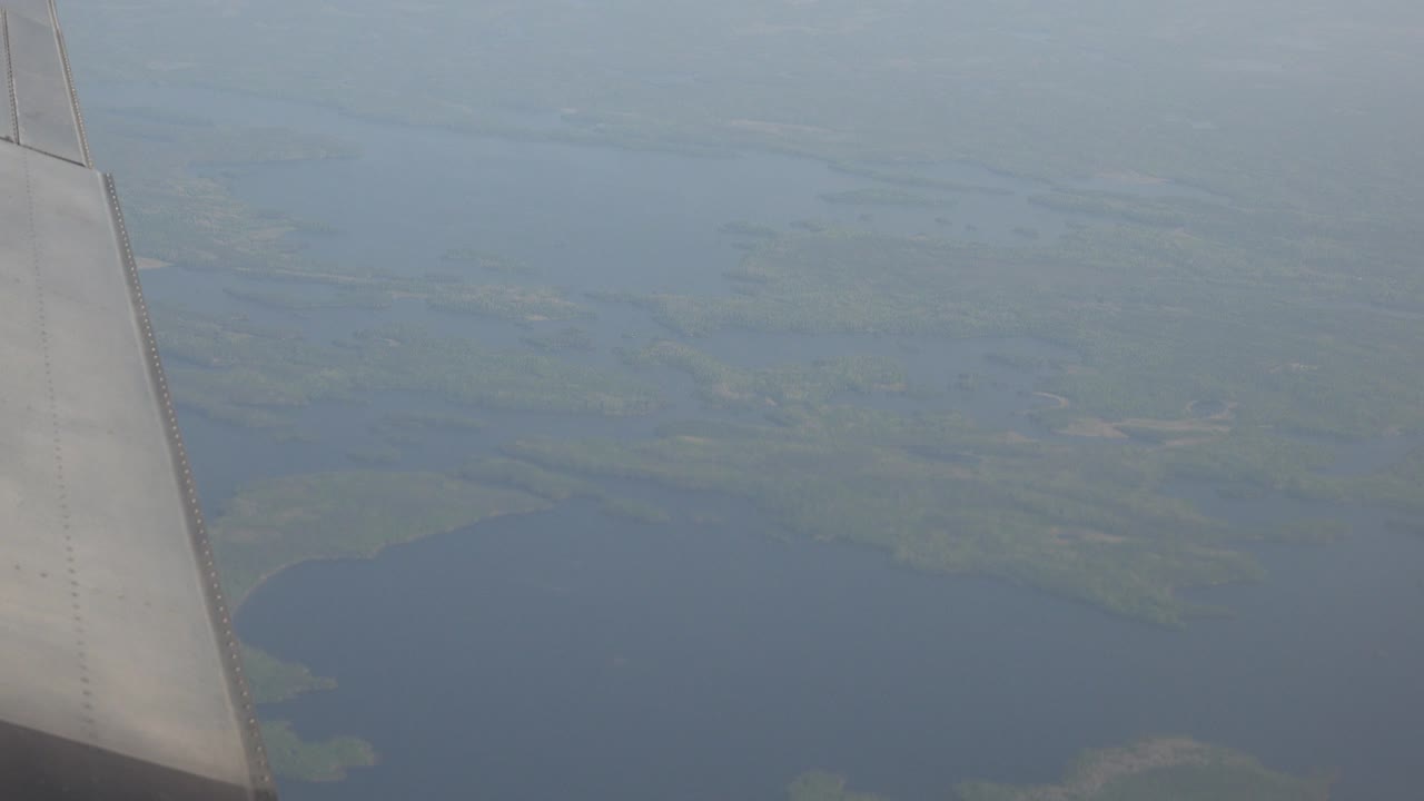 Aircraft wing remains on the left while blue water and green wetland shapes spread below in Red Lake, Canada, with no visible people.