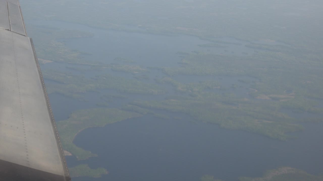 Plane wing over muted lake and wetland delta