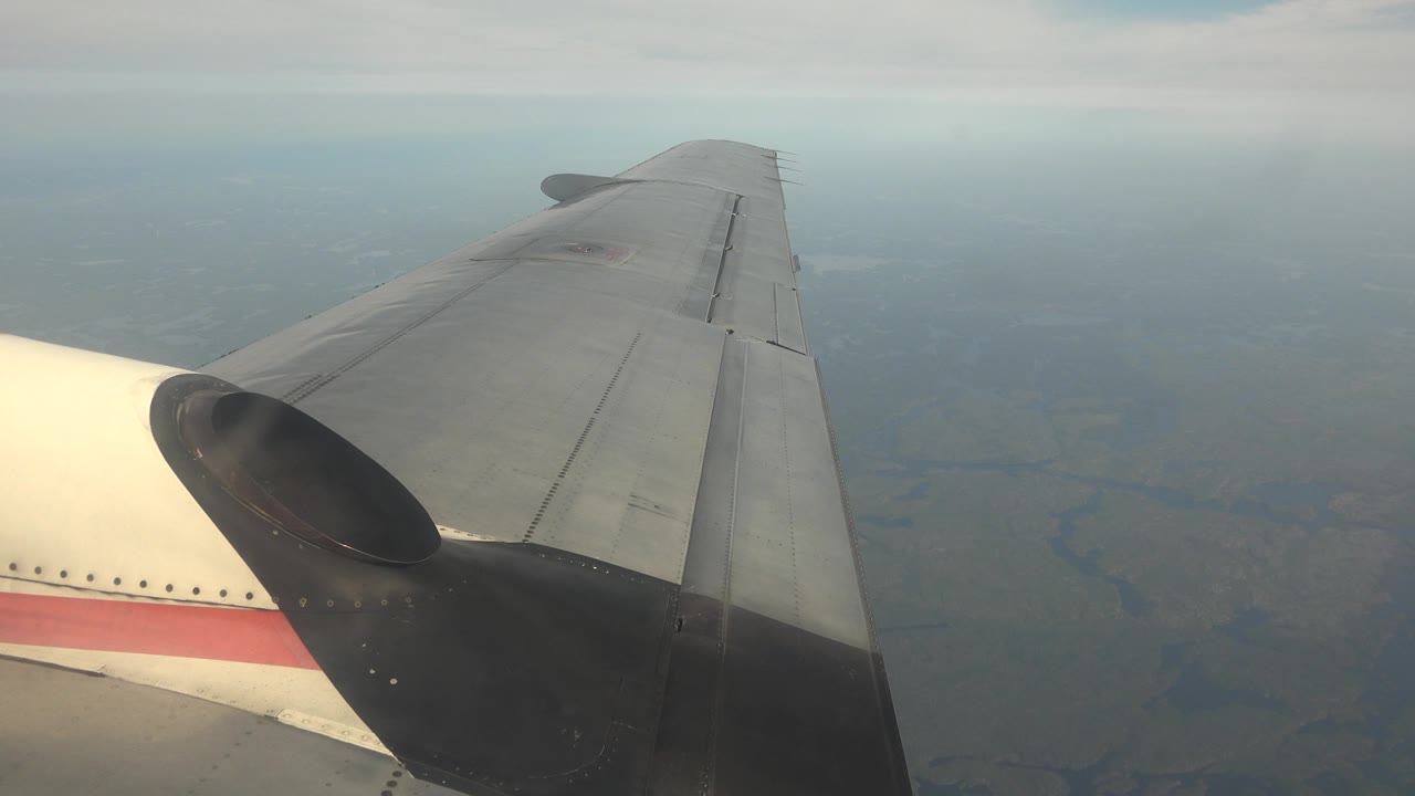 The aircraft wing stretches toward the upper right over a soft blue-gray horizon in Red Lake, Canada, with no visible people.
