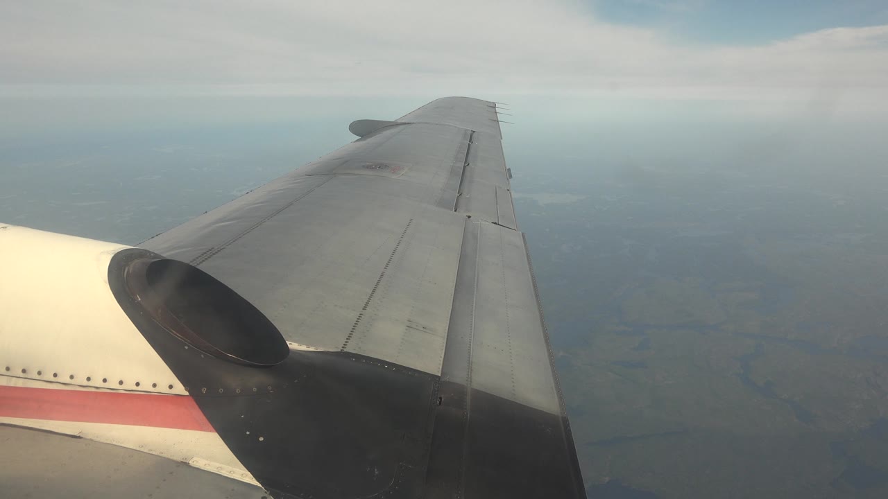 Aircraft wing over muted blue haze and land