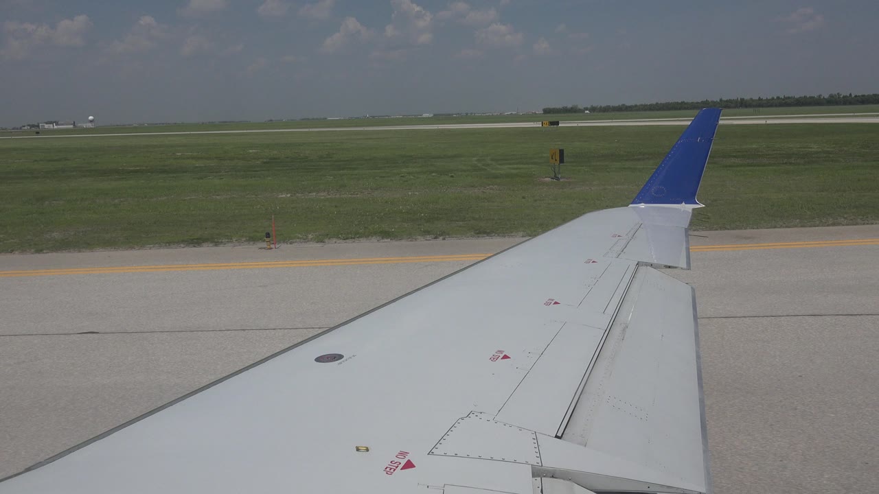 Airplane wing beside runway pavement and grass