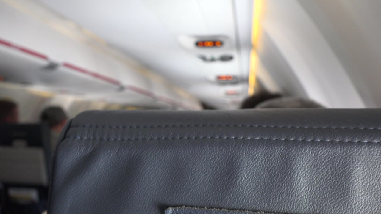 Airplane cabin seatback with overhead lights in soft focus