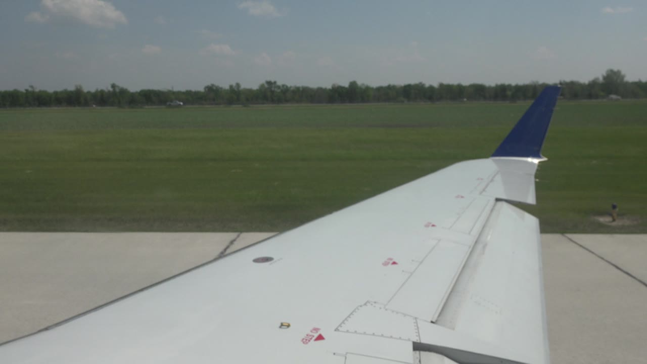 Airplane wing with runway slab and grassy background
