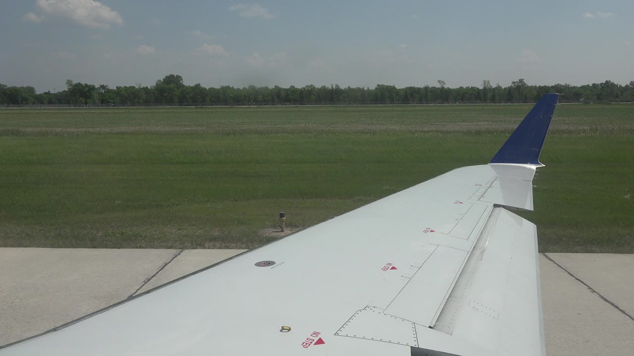 Airplane wing over runway pavement and grass
