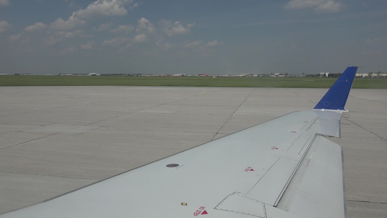 Airplane wing and blue winglet under scattered clouds