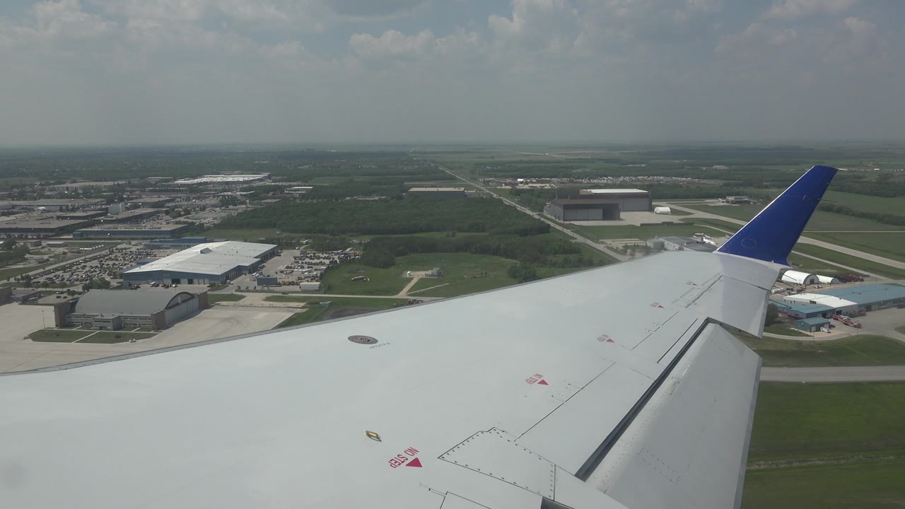 Airplane wing above airport buildings and runway area