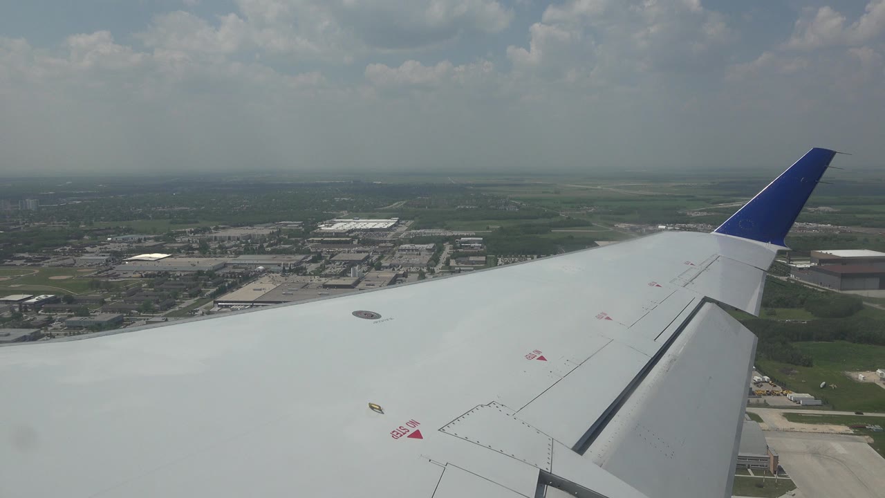 Airplane wing over airport grounds and distant city edge