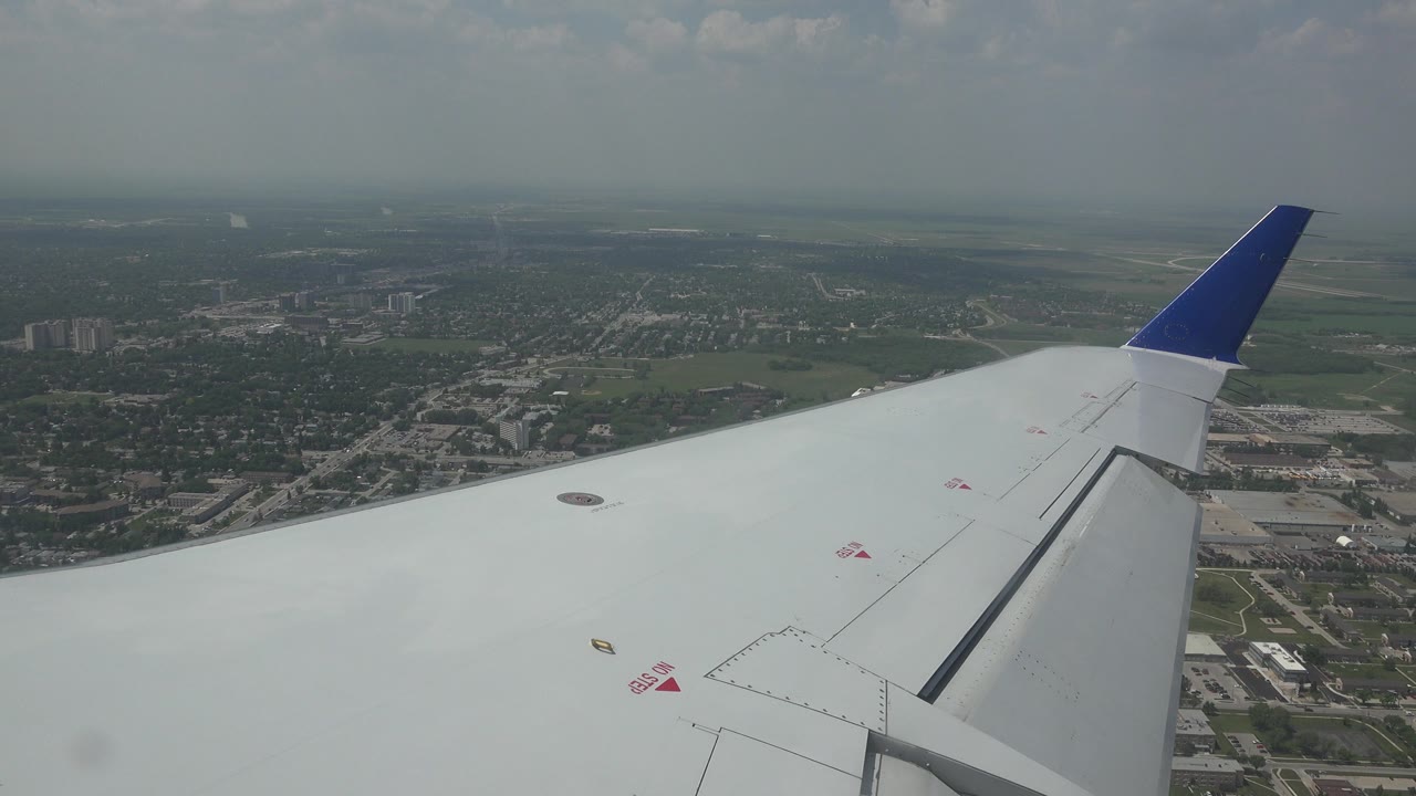 Airplane wing and blue wingtip over city edge.