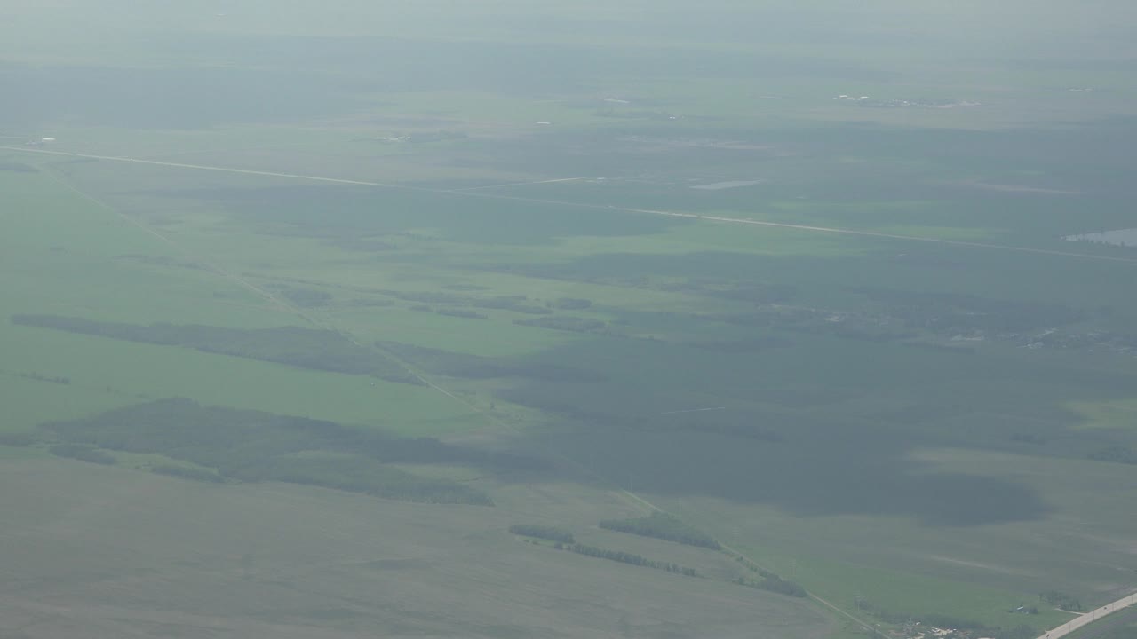 Green landscape seen from above through haze.
