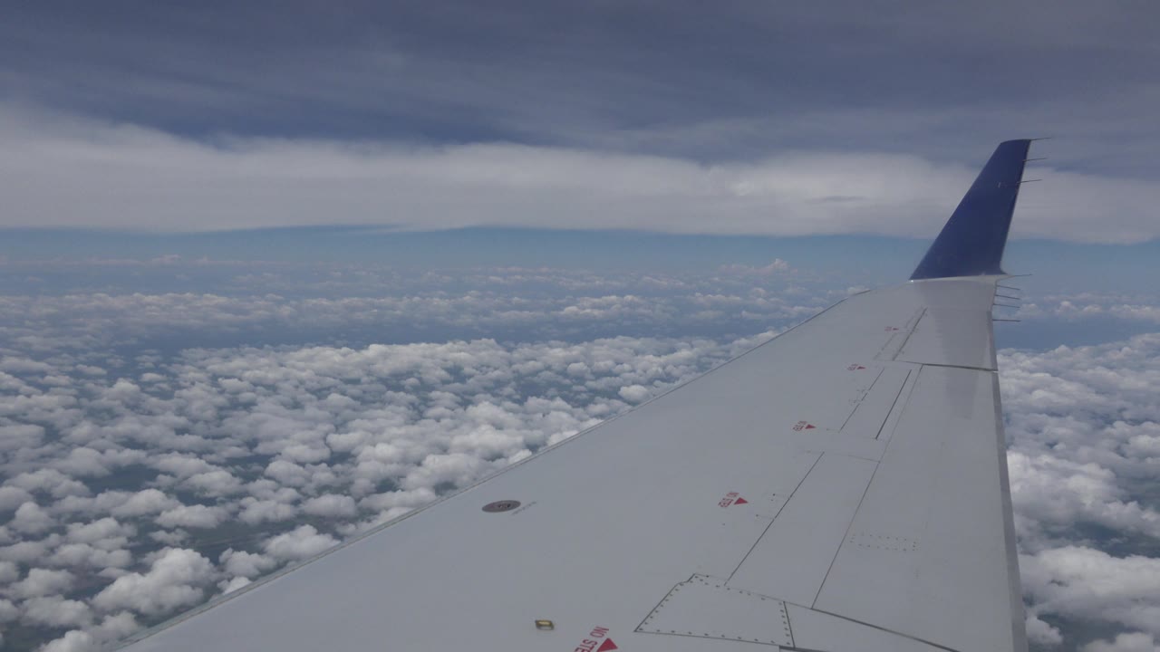 Second frame from the Winnipeg, Canada clip with the wing slightly farther across the foreground, broken cloud texture below, a pale blue horizon band, and no visible people.