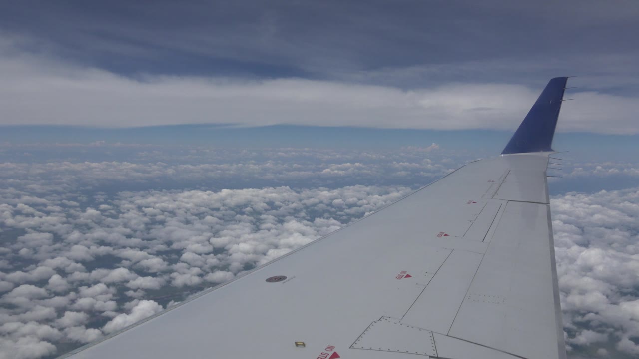 The second frame holds the gray wing in the foreground over textured clouds and faint ground far below near Winnipeg, Canada, with no visible people.