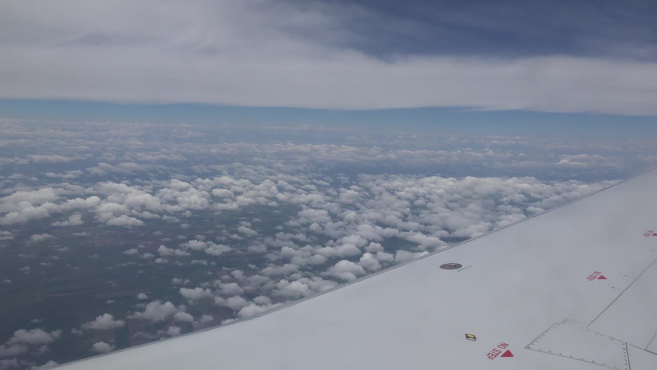 Plane wing and cloud tops viewed from high altitude.