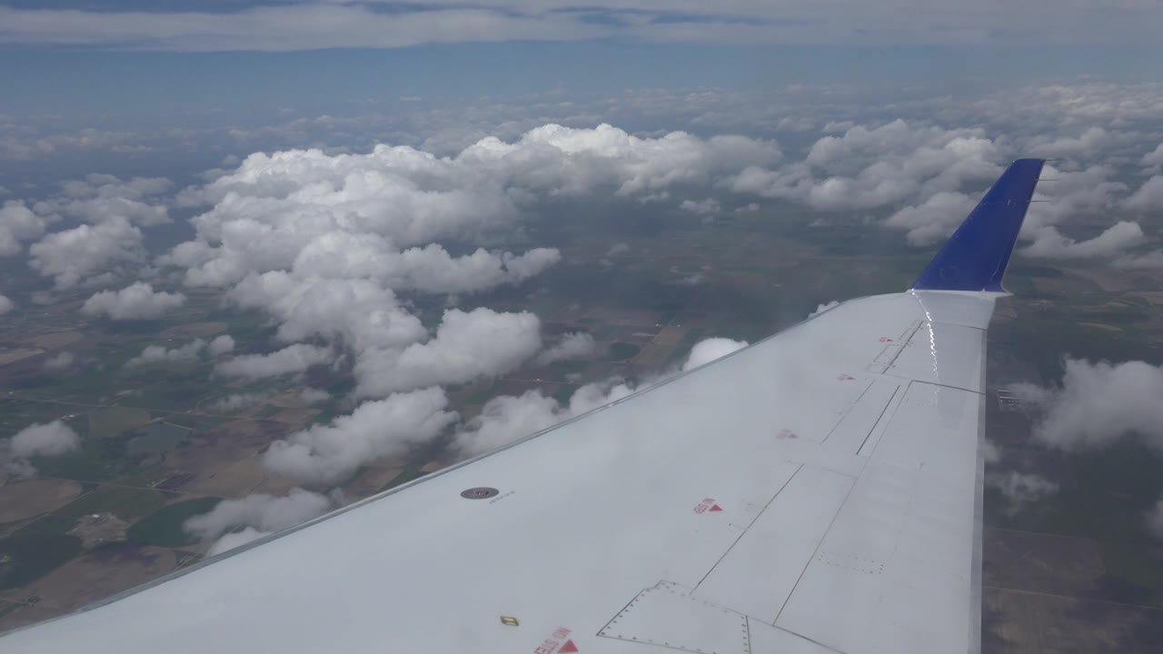 Airplane wing over cloud banks and distant land
