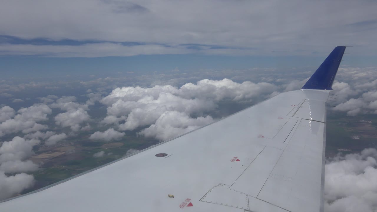 Plane wing and blue winglet over clouds
