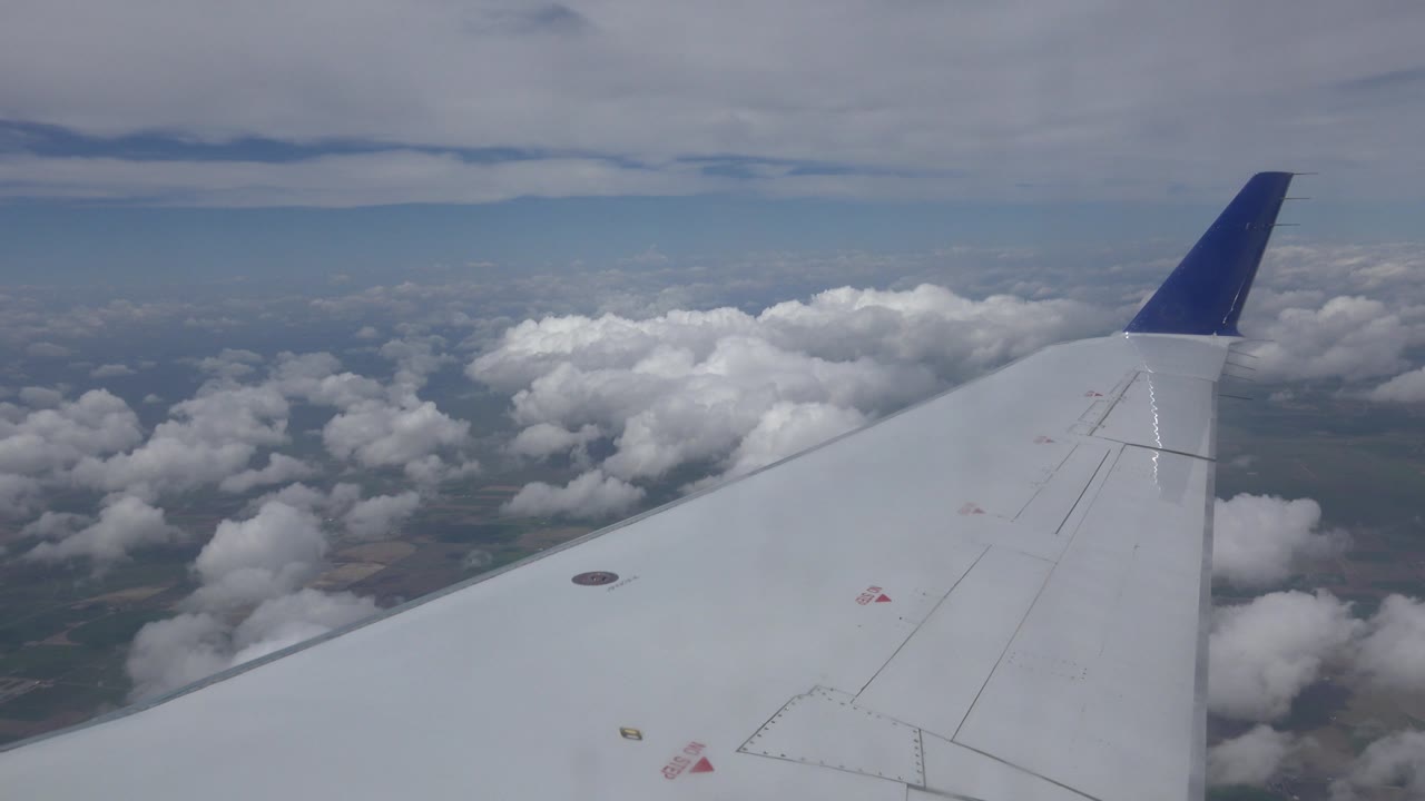 Aircraft wing with clouds below and sky above