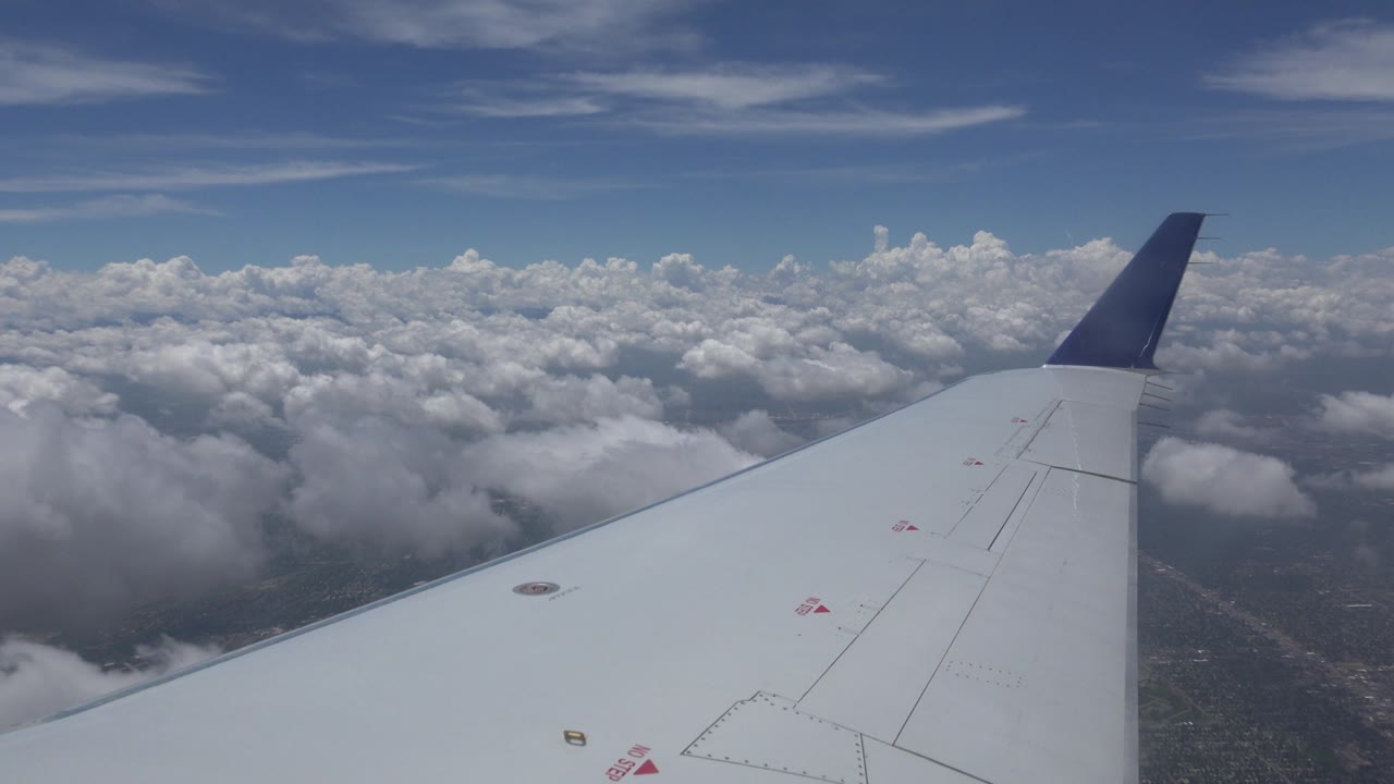 White wing crossing clouds from a passenger window