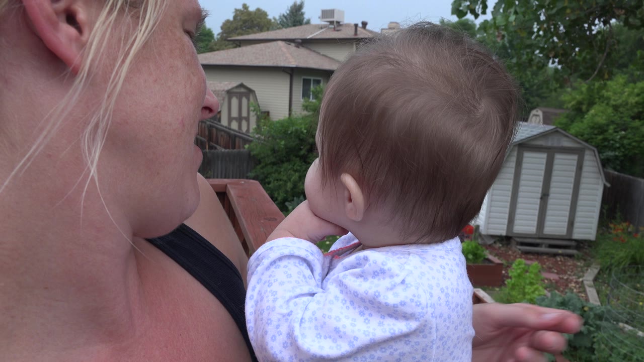 Mother holding baby as the baby's arm extends outward.