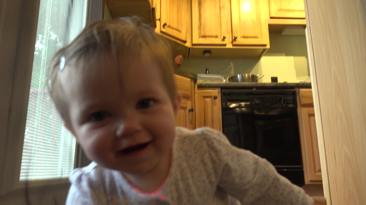 The baby remains near the lens with a slight smile, framed against warm wood kitchen cabinets and a black oven inside the Westminster, Colorado home.